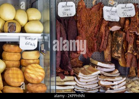 Handel mit geräuchertem Fleisch und Schweinefett. Käseköpfe in verschiedenen Farben und Größen werden auf der Theke gestapelt. Inschriften in rumänischer Sprache. Nahaufnahme. Selektiv für Stockfoto