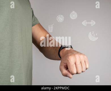 Fitbit, Fitness-Tracker, Schrittzähler, Smartwatch auf der Hand eines männlichen Athleten zur Überprüfung der Gesundheit, Schlaf, Aktivität, Training, Pulsmessung. Hochwertiger ph-wert Stockfoto