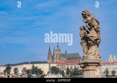 Prag, Tschechische Republik - 5. September 2022: Statue auf der Karlsbrücke und Prager Burg im Hintergrund Stockfoto
