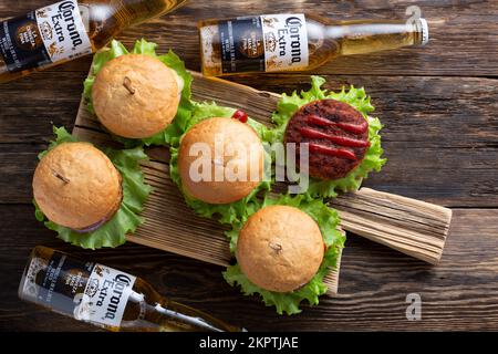 30.06.2022; Berlin; Deutschland; Korona-Bier und frische leckere Burger mit saftigen Fleischpasteten; Ketchup und Kräuter auf einem hölzernen Vintage-Tisch; Draufsicht; Resta Stockfoto