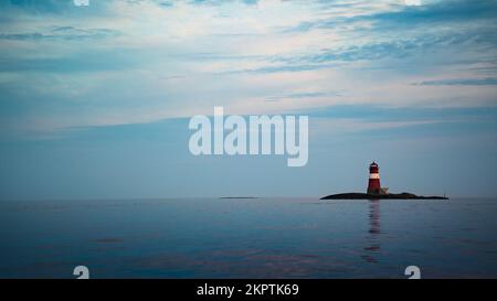 Der Leuchtturm auf einer kleinen Insel spiegelt sich im Wasser wider Stockfoto