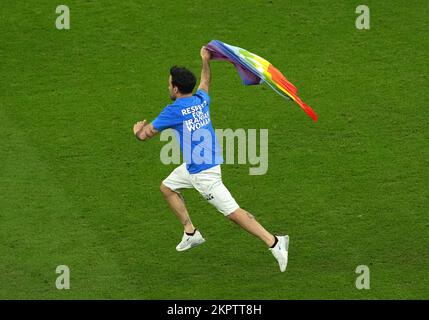 Während des Spiels der Gruppe H der FIFA-Weltmeisterschaft im Lusail-Stadion in Lusail, Katar, betritt ein Demonstrante in einer Top-Lesung „Respect for Iranian Women“ mit einer Regenbogenflagge das Spielfeld. Foto: Montag, 28. November 2022. Stockfoto