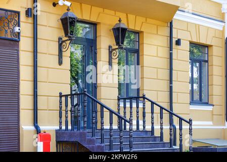 Ein Teil eines modernen, wunderschönen Eingangs eines Hauses mit Laternen, großen Fenstern und Eingangstüren mit Elementen des alten Stils. Stockfoto