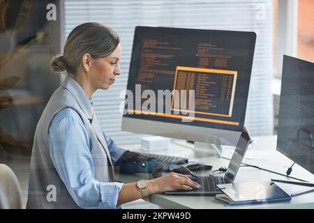Weibliche Softwareentwicklerin, die auf einem Laptop am Schreibtisch im Forschungszentrum codiert Stockfoto