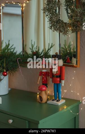 Spiegel über einem Sideboard in einem Wohnzimmer, dekoriert mit Lichterketten, Kranz, Weihnachtsdekorationen und Ornamenten Stockfoto