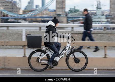 Eine Frau, die mit einem E-Bike über die London Bridge in London fährt. 17. November 2022 Stockfoto