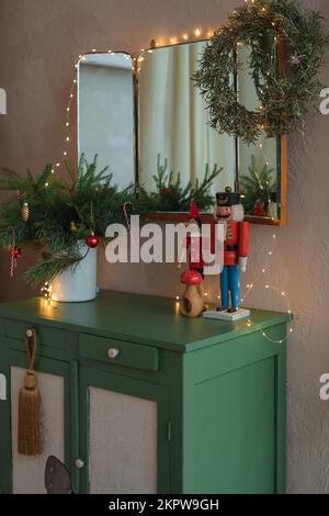 Spiegel über einem Sideboard in einem Wohnzimmer, dekoriert mit Lichterketten, Kranz, Weihnachtsdekorationen und Ornamenten Stockfoto