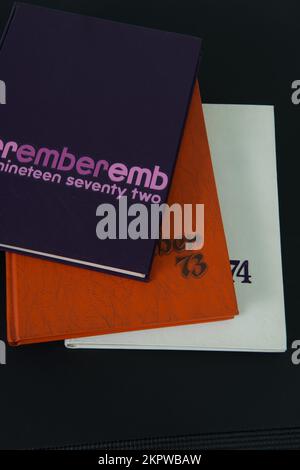 Lila, orangefarbene und weiße Highschool-Jahrbücher von 1972, 1973 und 1974 auf schwarzem Hintergrund. Stockfoto