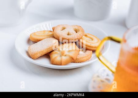 Tee wird in einem Glasbecher mit Keksen serviert. Idealer Snack zum Frühstück. Helle und weiße Szene. Stockfoto