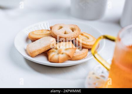 Tee wird in einem Glasbecher mit Keksen serviert. Idealer Snack zum Frühstück. Helle und weiße Szene. Stockfoto