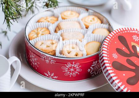 Dänische Butterkekse in einer roten Weihnachtsdose mit Schneeflocken und Hirschen. Weihnachtskekse. Stockfoto