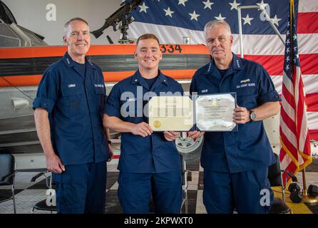 Coast Guard Petty Officer 3. Class Corey Connolly, ein Bootsmann des Coast Guard Maritime Safety & Security Team Houston, posiert für ein Foto mit Vice ADM. Kevin Lunday, Commander der Coast Guard Atlantic Area, Und ADM. Steven Poulin, Vizekommandant der Küstenwache, nachdem er einen Preis während eines Treffens mit allen Händen am MSST Houston, Texas, am 3. November 2022 erhalten hatte. Connolly erhielt am 2. Juni 2022 eine Medaille zur Erinnerung an die Küstenwache, weil er drei Leben auf dem Rio Grande an der Grenze zwischen den USA und Mexiko rettete. Stockfoto