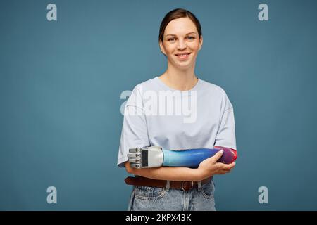 Studioporträt einer positiven jungen Frau mit bionischem Arm Stockfoto