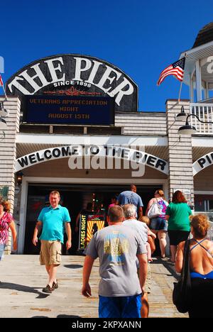 An einem Sommertag betreten und verlassen Besucher den historischen Pier am Old Orchard Beach in Maine Stockfoto