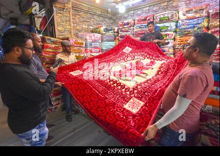 Dhaka. 28.. November 2022. Verkäufer zeigen Kunden am 23. November 2022 auf einem Markt in Dhaka, Bangladesch, eine chinesische Decke. Die Märkte in Dhaka sind jetzt vor der Hochsaison der Winterverkäufe voll ausgelastet. Dank ihrer Erschwinglichkeit und ihres attraktiven Designs ziehen mittlerweile viele Fachgeschäfte mit einer umfangreichen Sammlung chinesischer Decken viele Kunden an. Kredit: Xinhua/Alamy Live News Stockfoto