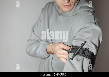 Eine Person legt einen Stauschlauch auf den Arm, um Blutungen während der ersten Hilfe zu verhindern. Ausbildung in taktischer Medizin. Kampfausrüstung Stockfoto