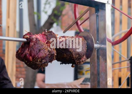 Prozess des Kochens großer Fleischstücke auf Spieß über offenem Feuer Stockfoto