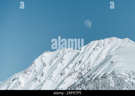 Der Mond erhebt sich über schneebedeckten Bergketten in den österreichischen alpen, Gastein, Salzburg, Österreich Stockfoto