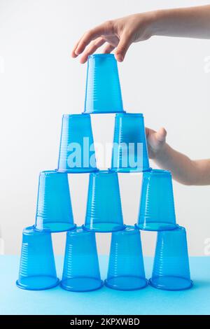 Pyramide aus blauen Plastikbechern. Bereit für die Party. Kinderhände Stockfoto