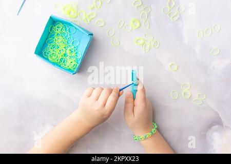 Konzept der Herstellung von Webstubenarmbändern durch Kinder in Blau und Gelb Stockfoto