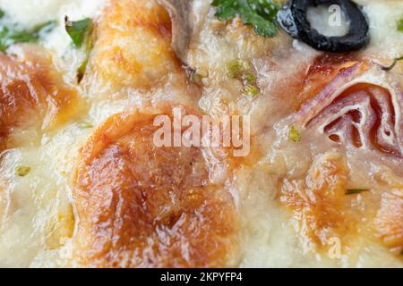 Makroaufnahme von italienischer Pizza mit Mozzarella und Kirschtomaten, Pilzen und roten Zwiebeln, Gewürzen, Ketchup und Paprika. Italienische Küche. Stockfoto