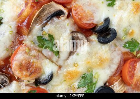 Makroaufnahme von italienischer Pizza mit Mozzarella und Kirschtomaten, Pilzen und roten Zwiebeln, Gewürzen, Ketchup und Paprika. Italienische Küche. Stockfoto