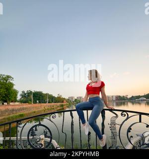 Eine Frau, die auf dem Geländer in Kaliningrad sitzt. Stockfoto