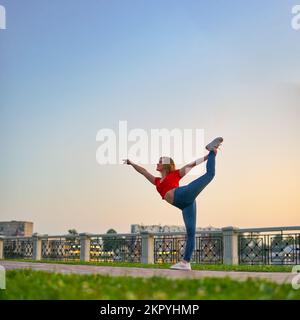 Junge Frau, die am Abend Dehnungsübungen macht. Stockfoto
