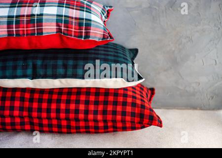 Nahaufnahme eines Stapels verschiedener Kissen mit verschiedenen Karomustern auf einem Regal Stockfoto