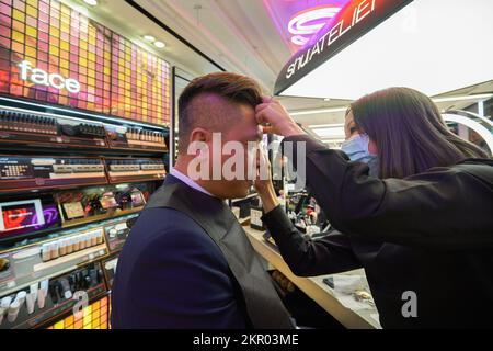 HONGKONG - CIRCA DEZEMBER 2019: Kosmetikberater arbeitet mit männlichen Kunden im Shu Uemura Store im Harbour City Shopping Centre. Stockfoto