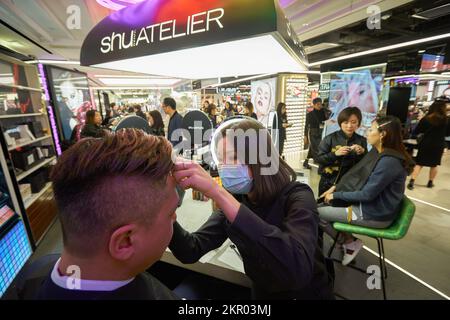 HONGKONG - CIRCA DEZEMBER 2019: Kosmetikberater arbeitet mit männlichen Kunden im Shu Uemura Store im Harbour City Shopping Centre. Stockfoto