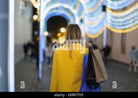 Eine junge Frau auf dem Rücken, die zu weihnachten Einkaufstüten mit sich herumträgt Stockfoto