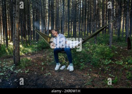 Junge und Mädchen spielen in einer Hängematte im Wald Stockfoto