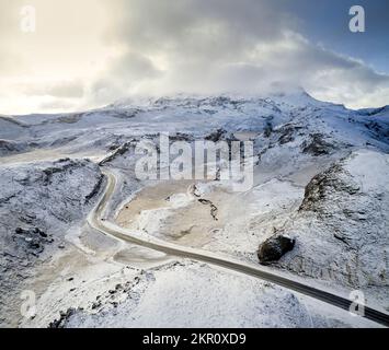 Asphaltstraße zwischen dem schneebedeckten Bergtal im Winter Stockfoto