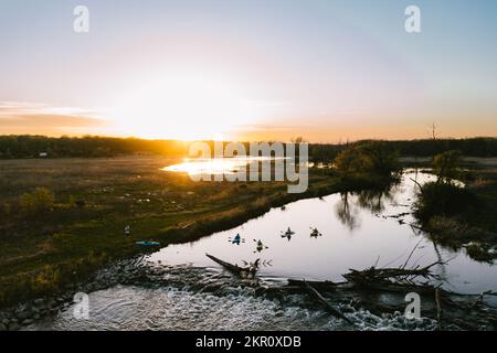 Vier Personen Kajak auf dem Fluss bei Sonnenuntergang in einem Waldschutzgebiet Stockfoto