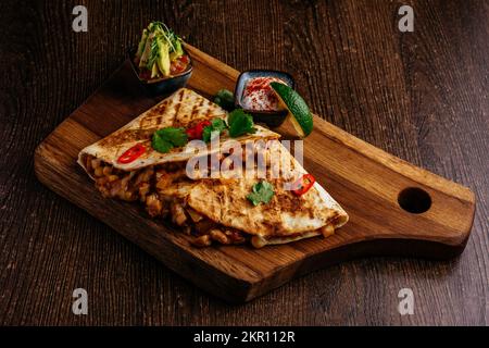 mexikanische Quesadilla mit Huhn und scharfer Sauce auf einem Brett Stockfoto