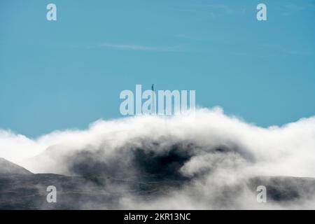 Blauer Himmel über dem Berg mit hohem Turm bedeckt mit Nebel Stockfoto