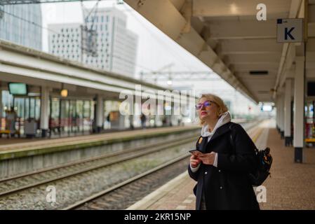 Eine Frau auf dem Bahnsteig, die nach dem Zug sucht Stockfoto