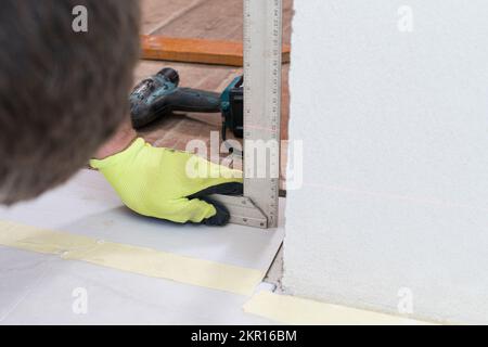 Montage der Innentüren, Messung der vertikalen Ebene unter Verwendung einer Ebene während der Türmontage, Reparaturarbeiten. Stockfoto