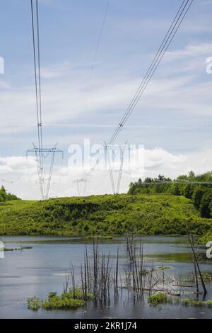 Stromübertragungstürme mit Kabeln überfluteten Süßwassermarsch mit toten Bäumen im Frühling, Laurentianer, Quebec, Kanada. Stockfoto