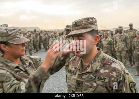 Harringson Castrillon, ein Spezialist für taktische Stromerzeuger bei der 369. Nachhaltigkeitsbrigade, erhielt am 4. November 2022 eine neue Patrouillenkappe von 1. Sgt. Rebecca Santana, Hauptquartier und Hauptquartier der Kompanie 369. Nachhaltigkeitsbrigade First Sergeant, während einer Ehrungszeremonie in Camp Arifjan, Kuwait. Stabsvorsteher Castrillon wurde aus dem Rang eines Sergeants befördert. 369SB, 369th Sustainment Brigade, Harlem Hellfighters, NYNG, TF Hellfighter, Promotions, Stockfoto
