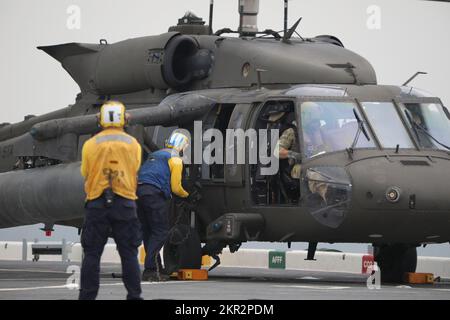 USA Army UH-60m Black Hawk Helikopter führt eine Deckslandung auf der USS Lewis B. Puller im Persischen Golf durch, 10. November 2022. Zwei US-Dollar Armee UH-60m Black Hawk Hubschrauber mit 3.. Bataillon, 142.. Luftfahrtregissement, Angriffshopter-Bataillon, angeschlossen an die 36.. Kampfluftfahrtbrigade, Und zwei AH-64E Apache-Hubschrauber mit 1.. Bataillon, 101.. Luftfahrtregiment, Attack Helicopter Bataillon, angeschlossen an das 36. CAB, führten Deckslandungen durch, um die Betriebsverfahren der USA zu erlernen Die Marine. 36. CAB, mobilisiert als Task Force Mustang, bietet eine ganze Armee-Oper an Stockfoto