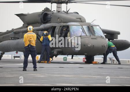 USA Army UH-60m Black Hawk Helikopter führt eine Deckslandung auf der USS Lewis B. Puller im Persischen Golf durch, 10. November 2022. Zwei US-Dollar Armee UH-60m Black Hawk Hubschrauber mit 3.. Bataillon, 142.. Luftfahrtregissement, Angriffshopter-Bataillon, angeschlossen an die 36.. Kampfluftfahrtbrigade, Und zwei AH-64E Apache-Hubschrauber mit 1.. Bataillon, 101.. Luftfahrtregiment, Attack Helicopter Bataillon, angeschlossen an das 36. CAB, führten Deckslandungen durch, um die Betriebsverfahren der USA zu erlernen Die Marine. 36. CAB, mobilisiert als Task Force Mustang, bietet eine ganze Armee-Oper an Stockfoto