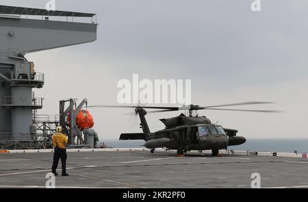 USA Army UH-60m Black Hawk Helikopter führt eine Deckslandung auf der USS Lewis B. Puller im Persischen Golf durch, 10. November 2022. Zwei US-Dollar Armee UH-60m Black Hawk Hubschrauber mit 3.. Bataillon, 142.. Luftfahrtregissement, Angriffshopter-Bataillon, angeschlossen an die 36.. Kampfluftfahrtbrigade, Und zwei AH-64E Apache-Hubschrauber mit 1.. Bataillon, 101.. Luftfahrtregiment, Attack Helicopter Bataillon, angeschlossen an das 36. CAB, führten Deckslandungen durch, um die Betriebsverfahren der USA zu erlernen Die Marine. 36. CAB, mobilisiert als Task Force Mustang, bietet eine ganze Armee-Oper an Stockfoto