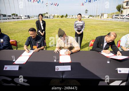 Von links: Akira Nakamatsu, Vizebürgerin von Chatan, Okinawa, USA Generalmajor des Marine Corps, Stephen E. Liszewski, kommandierender General der Marine Corps Installations Pacific, und Masanori Matsugawa, Bürgermeister von Ginowan, Okinawa, unterzeichnen am 7. November 2022 eine lokale Durchführungsvereinbarung für Camp Foster, Okinawa, Japan. Die LIA für begrenzte Katastrophenvorsorge ermöglicht den Evakuierten einen schnellen und direkten Weg in höhere Gebiete oder Unterkünfte auf teilnehmenden Stützpunkten des Marine Corps unmittelbar vor, während oder nach einer Naturkatastrophe. Die Unterzeichnung ist ein wichtiger Schritt zum Schutz der Bürger der Gemeinde Stockfoto
