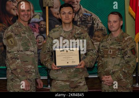 USA Army CPL. Liam Crawford (Mitte) erhält eine Military Outstanding Volunteer Service Medal von Major General John Meyer III (links), kommandierendem General der 1.. Infanteriedivision und Fort Riley, und Kommandodirektor Major Christopher Mullinax (rechts), KommandoSergeant Major der 1.. Inf. Div Und Fort Riley, 7. November 2022, in der Victory Hall in Fort Riley, Kansas. Crawford erhielt die Medaille für seine ehrenamtliche Arbeit bei der United Service Organization. Stockfoto