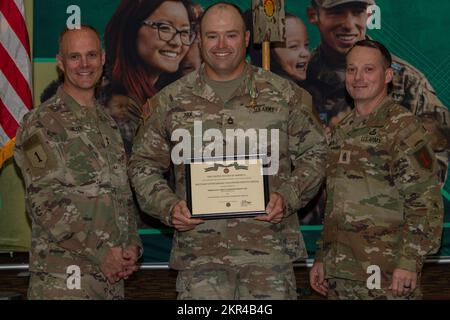 USA Army Sgt. 1.. Klasse Matthew Nix (Mitte) erhält eine Military Outstanding Volunteer Service Medaille von Major General John Meyer III (links), kommandierendem General der 1.. Infanteriedivision und Fort Riley, und Kommandodirektor Major Christopher Mullinax (rechts), dem KommandoSergeant Major der 1.. Div Und Fort Riley, 7. November 2022, in der Victory Hall in Fort Riley, Kansas. Nix erhielt die Medaille für seine ehrenamtliche Arbeit als Coach für ein Softballteam von Kansas Travel. Stockfoto