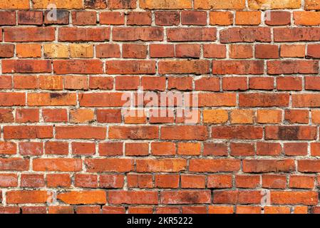 Verwitterte rote Backsteinwände im Hintergrund einer rustikalen alten Bauernhauswand Stockfoto