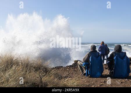 Bei einer großen Flut in Yachats, Oregon, sehen Zuschauer riesige Wellen an der felsigen Küste krachen. Stockfoto