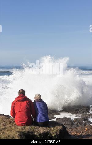 Bei einer großen Flut in Yachats, Oregon, sehen Zuschauer riesige Wellen an der felsigen Küste krachen. Stockfoto